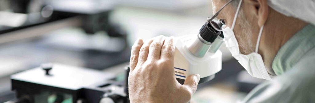 Employee of the German metal etching company micrometal looking through a microscope